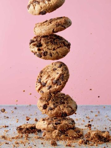 Chocolate chip cookies falling through the air and landing in cookie crumbles.