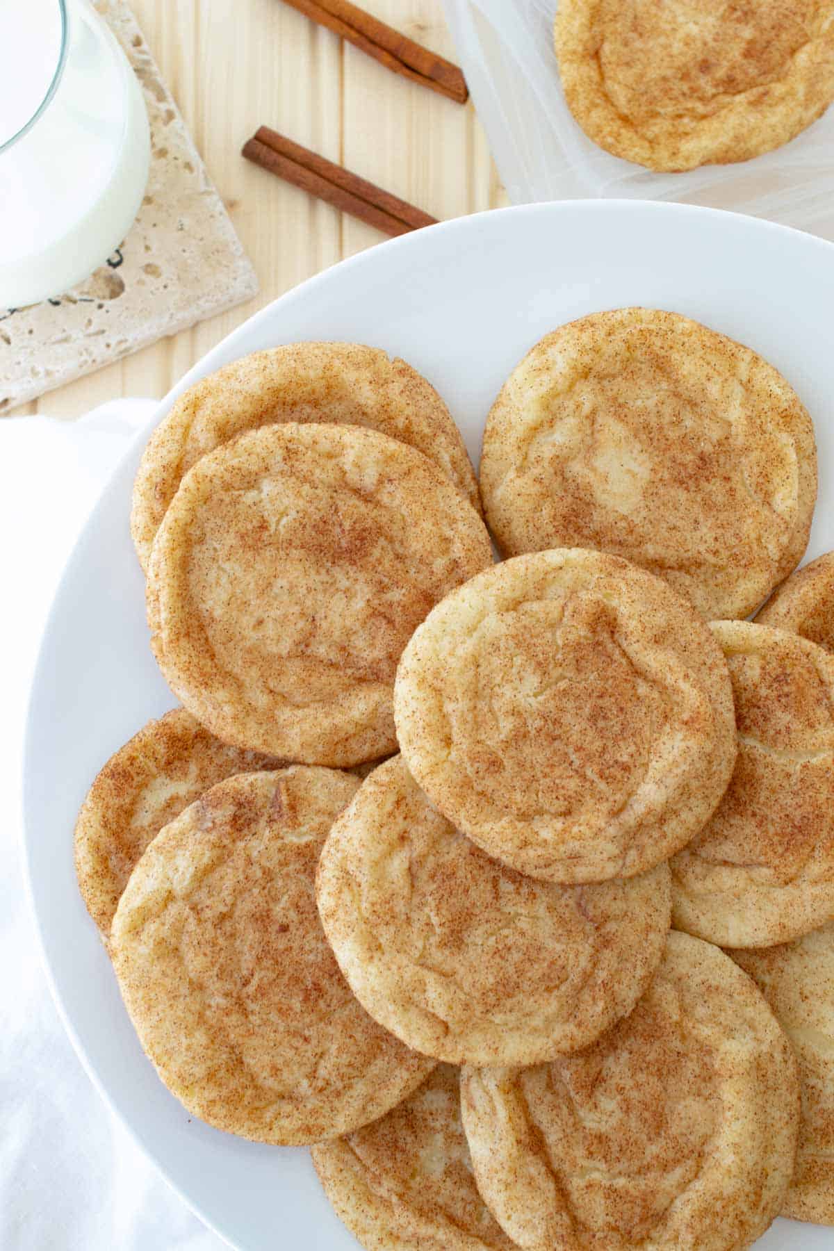 Plate of snickerdoodle cookies with a glass of milk in the background.