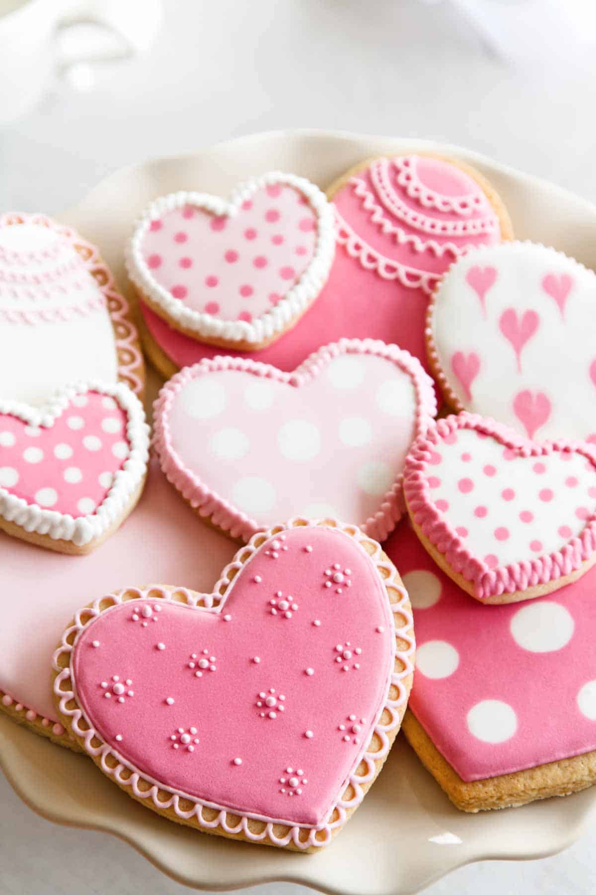 Plate of heart-shaped sugar cookies decorated with royal icing.