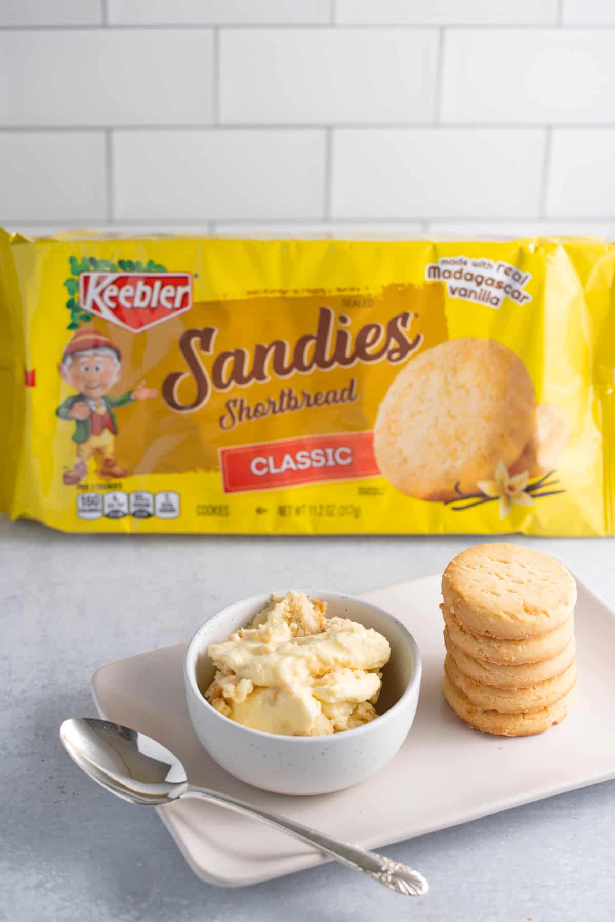 A bowl of banana pudding made with shortbread cookies with a box of Sandies shortbread cookies in the background.