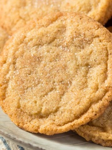 Close up of a single snickerdoodle cookie on top of a pile of snickerdoodles on a plate.