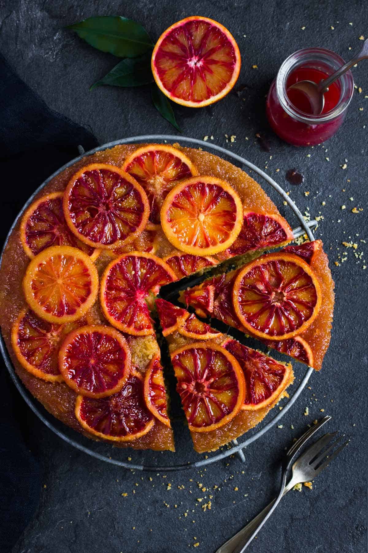 Upside down blood orange cake on a cooling rack. Two slices are cut from it, but are still on the rack.