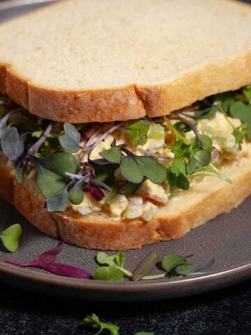 Chicken salad sandwich topped with microgreens.