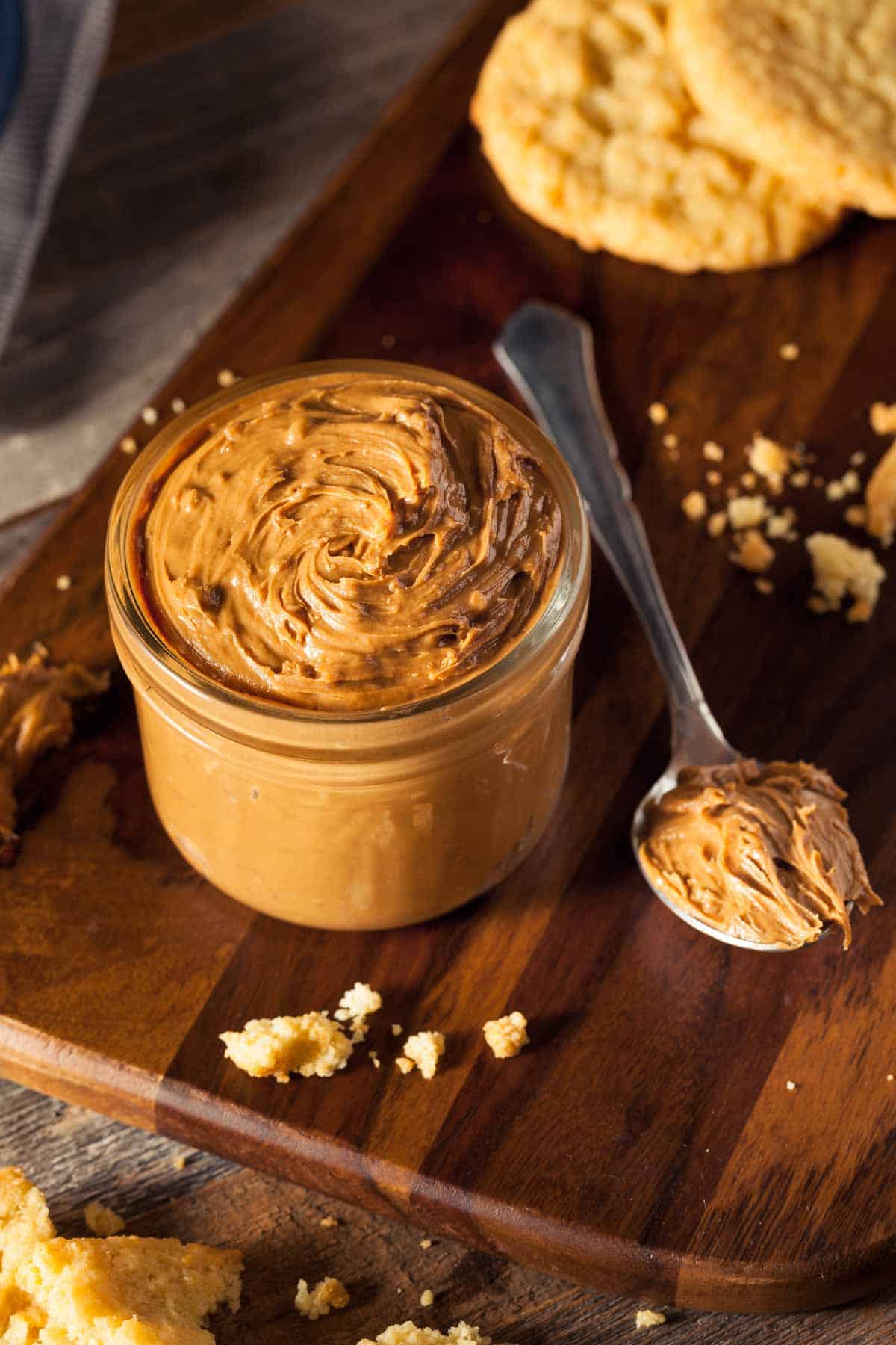 Jar of cookie butter with cookie butter cookies in the background.