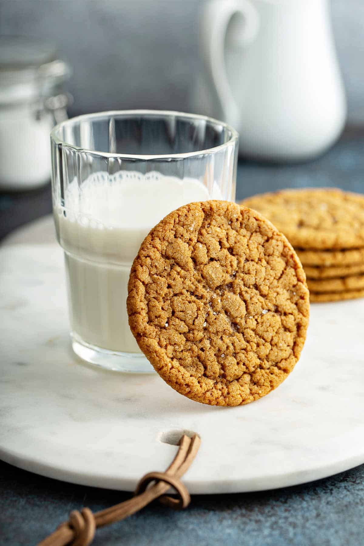 Gingersnap cookie propped against a glass of milk.