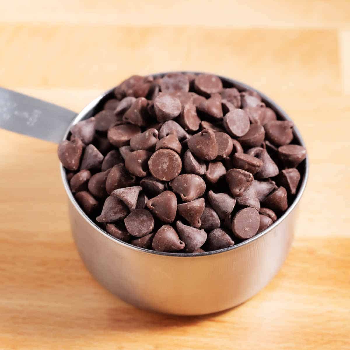 Metal measuring cup filled with chocolate chips.