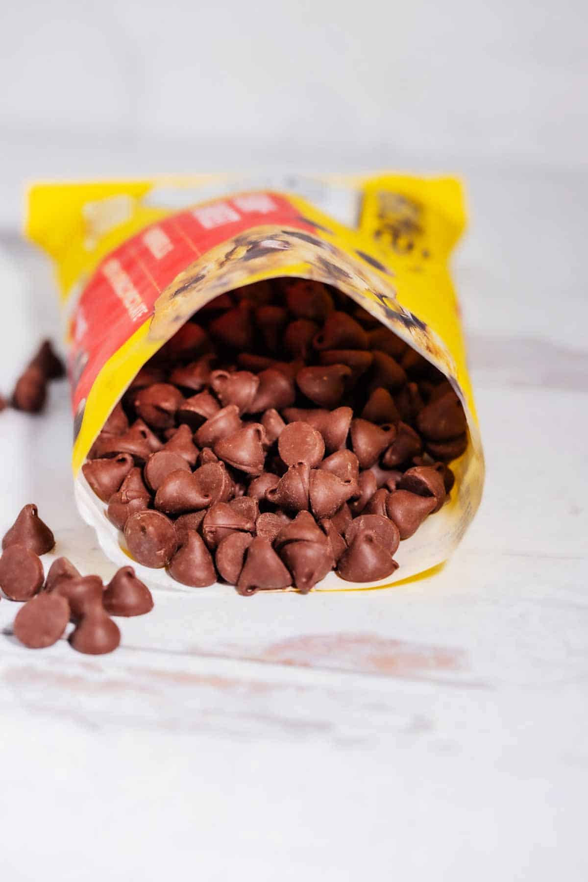 A bag of milk chocolate chips with the end opened so that you can see inside.