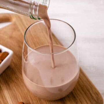 Pouring chocolate almond milk into a glass.