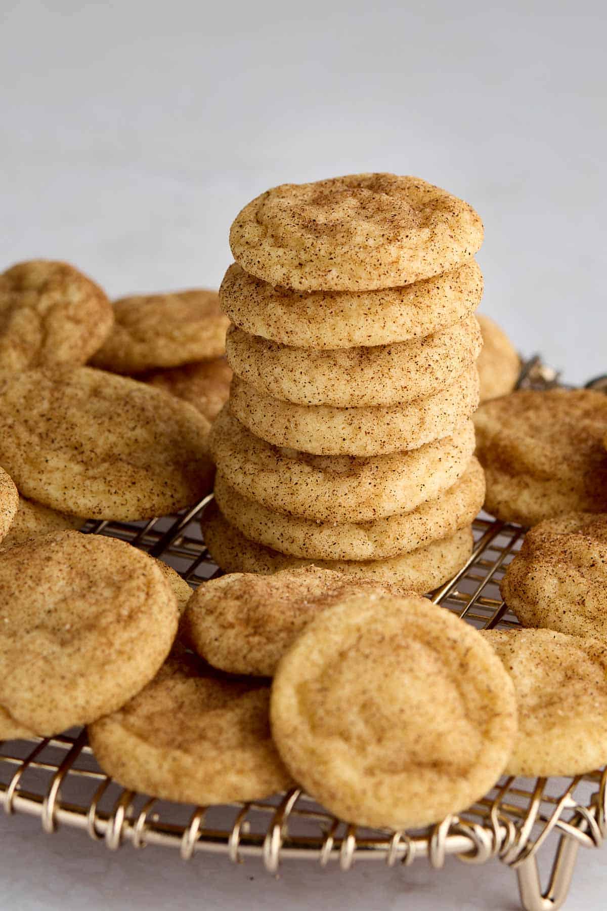 A stack of mini snickerdoodle cookies on a cooling rack surrounded by other mini cookies.