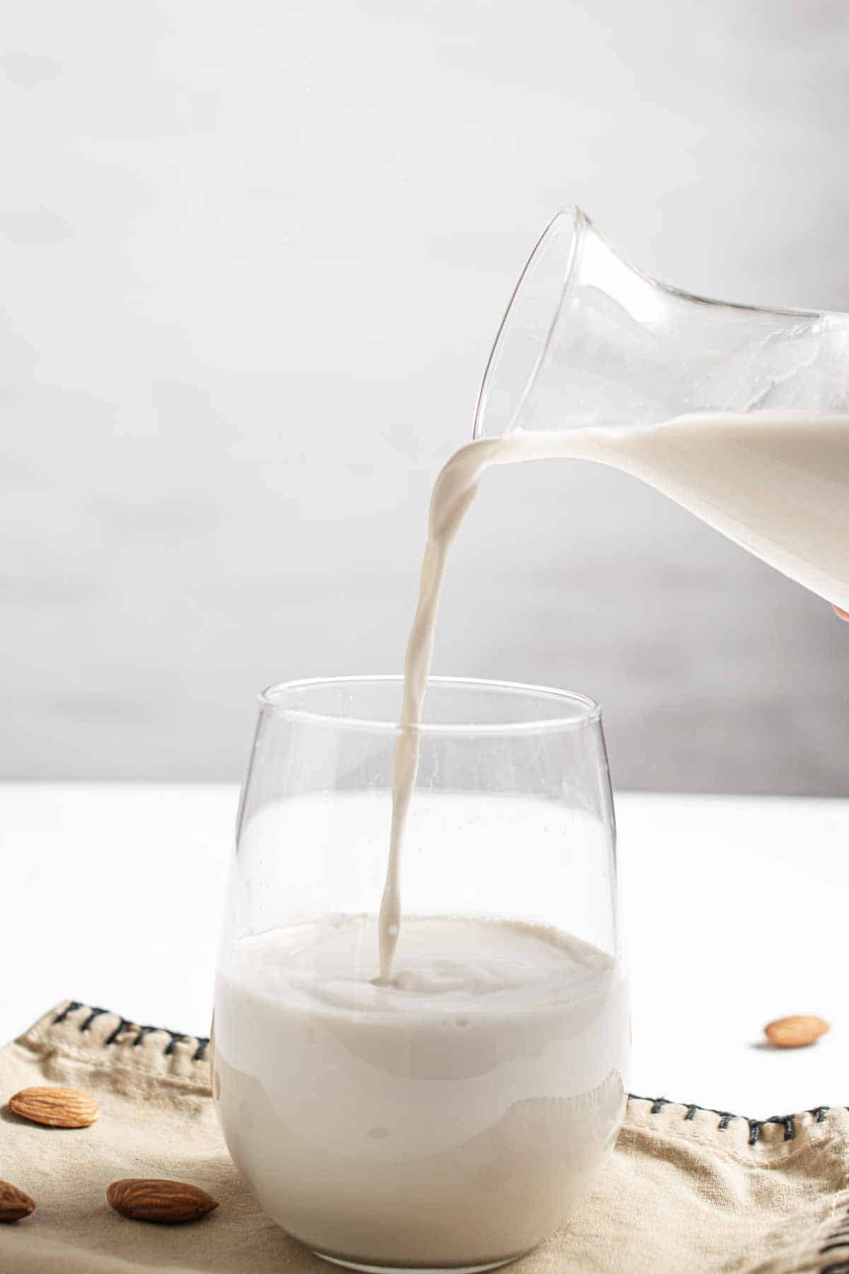 Pouring homemade almond milk into a glass.