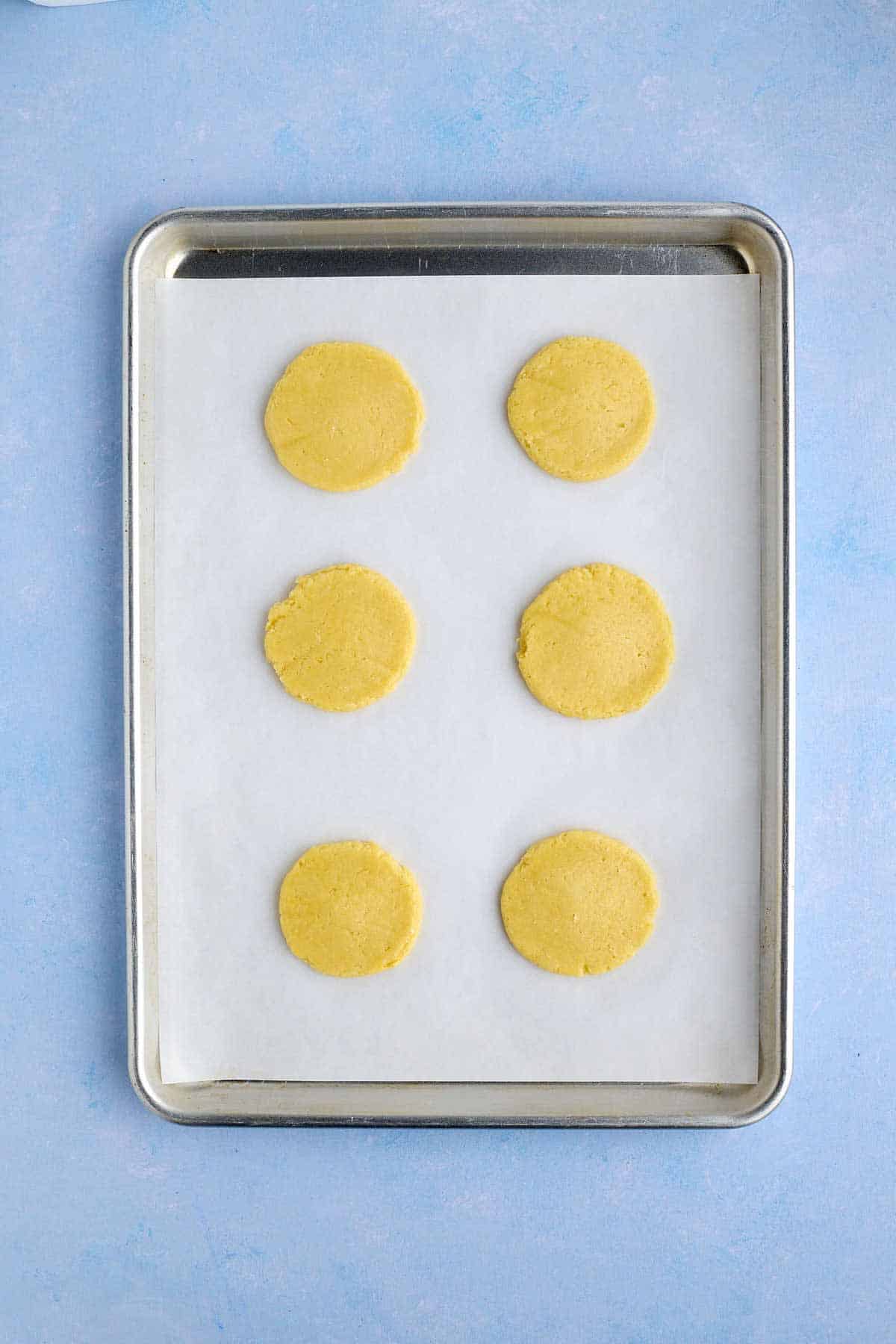 Flattened pineapple cookie dough on a cookie sheet ready to go in the oven.