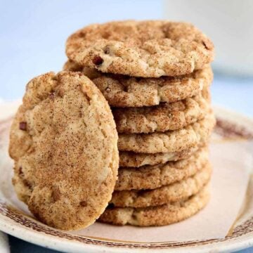 Stack of butter pecan cake mix cookies on a plate with one cookie leaning against the stack.