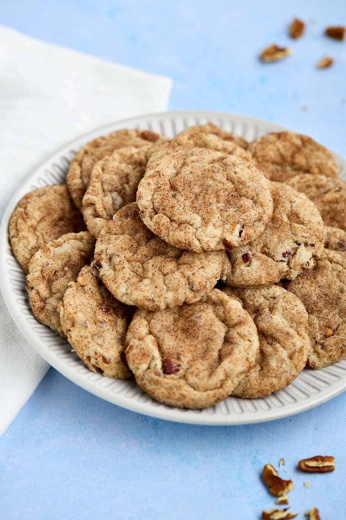 Plate of butter pecan cake mix cookies with pecans scattered around.