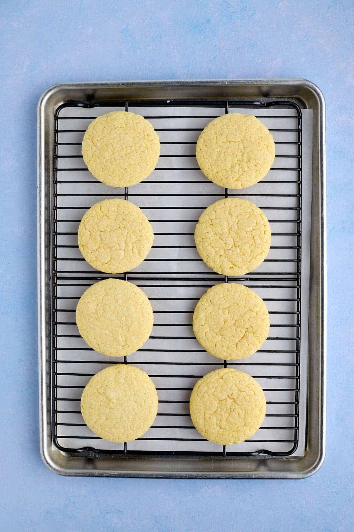 Baked cookies on a cooling rack with parchment paper underneath to catch and glaze spills.