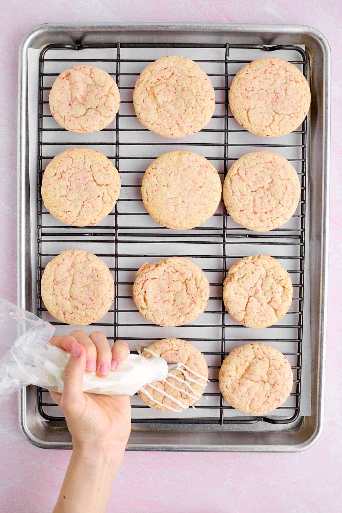 Drizzling melted white chocolate on cherry chip cookies.