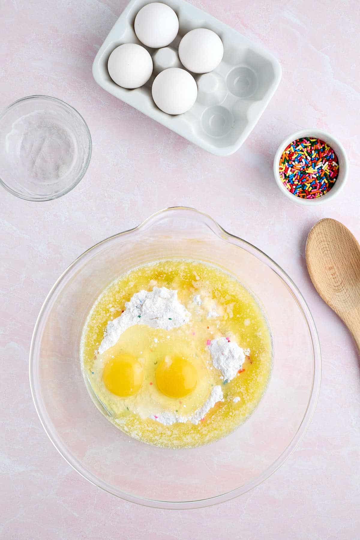 Melted butter and eggs added to bowl of Funfetti cake mix for cookies.