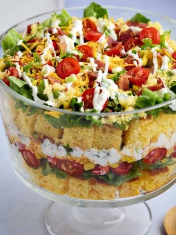 Layered cornbread salad without beans in a glass serving dish revealing the ingredient layers.