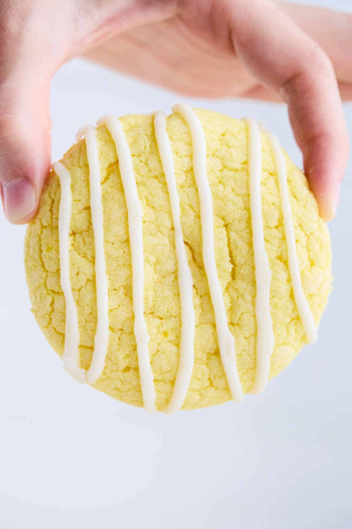 Fingers holding a single lemon cake mix cookie.