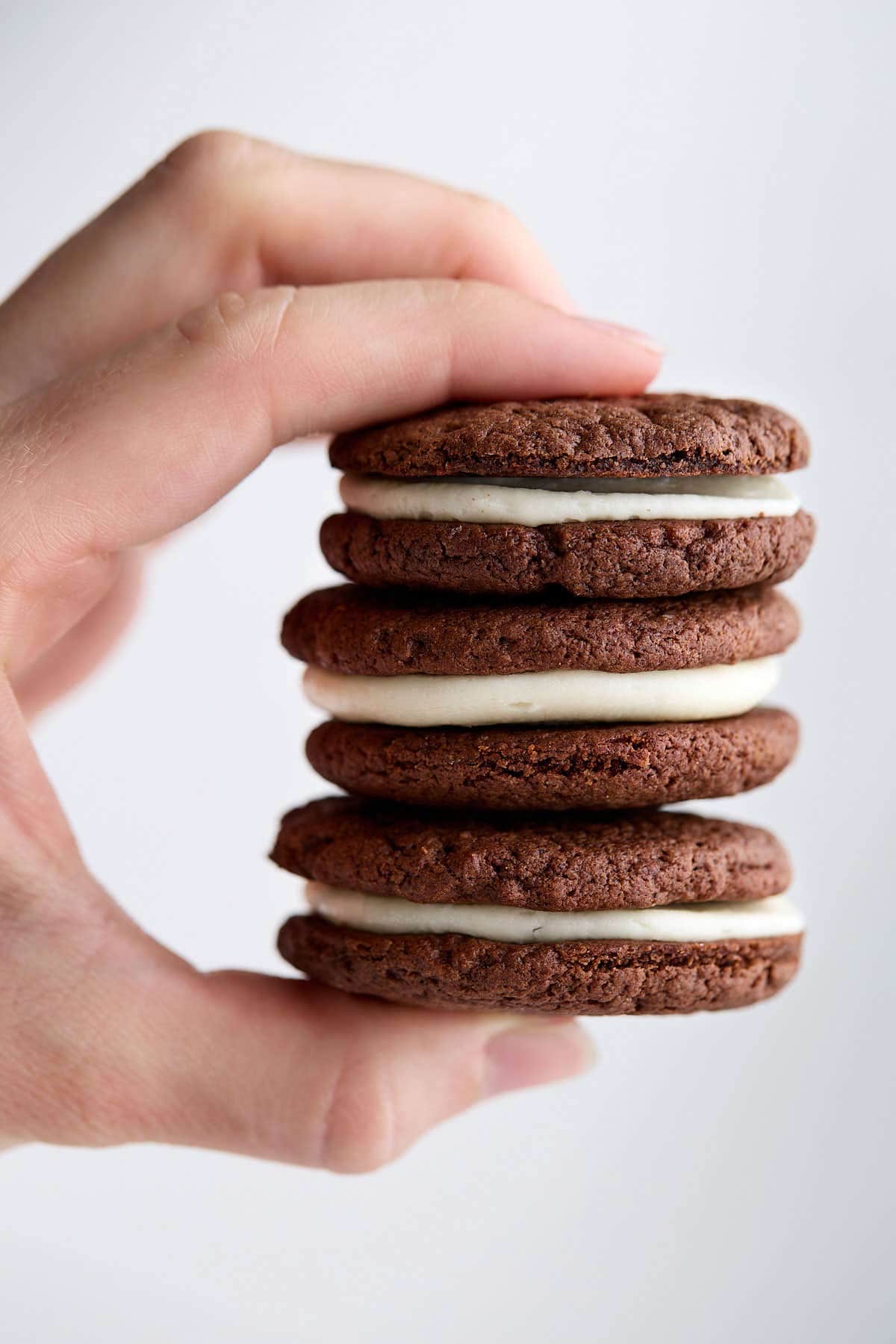 Fingers holding a stack of 3 Oreo cake mix cookies.