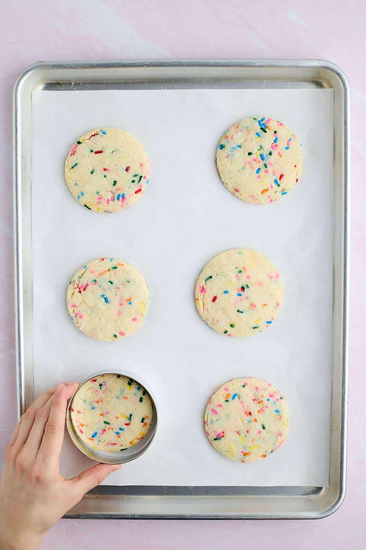Shaping the warm Funfetti cookies with a cookie ring on a baking sheet.