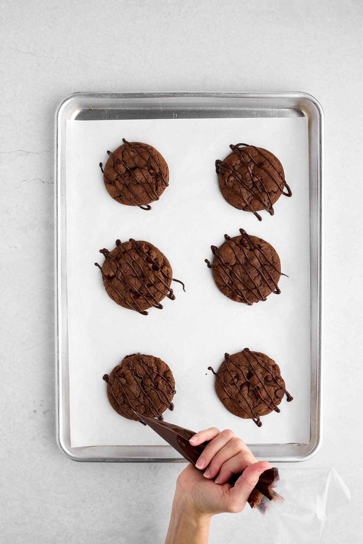 Drizzling melted chocolate on devil's food cake mix cookies.