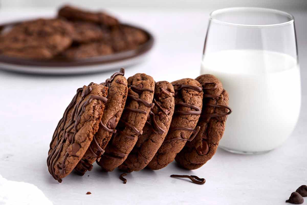 Devil's food chocolate chip cookies leaning against a glass of milk.