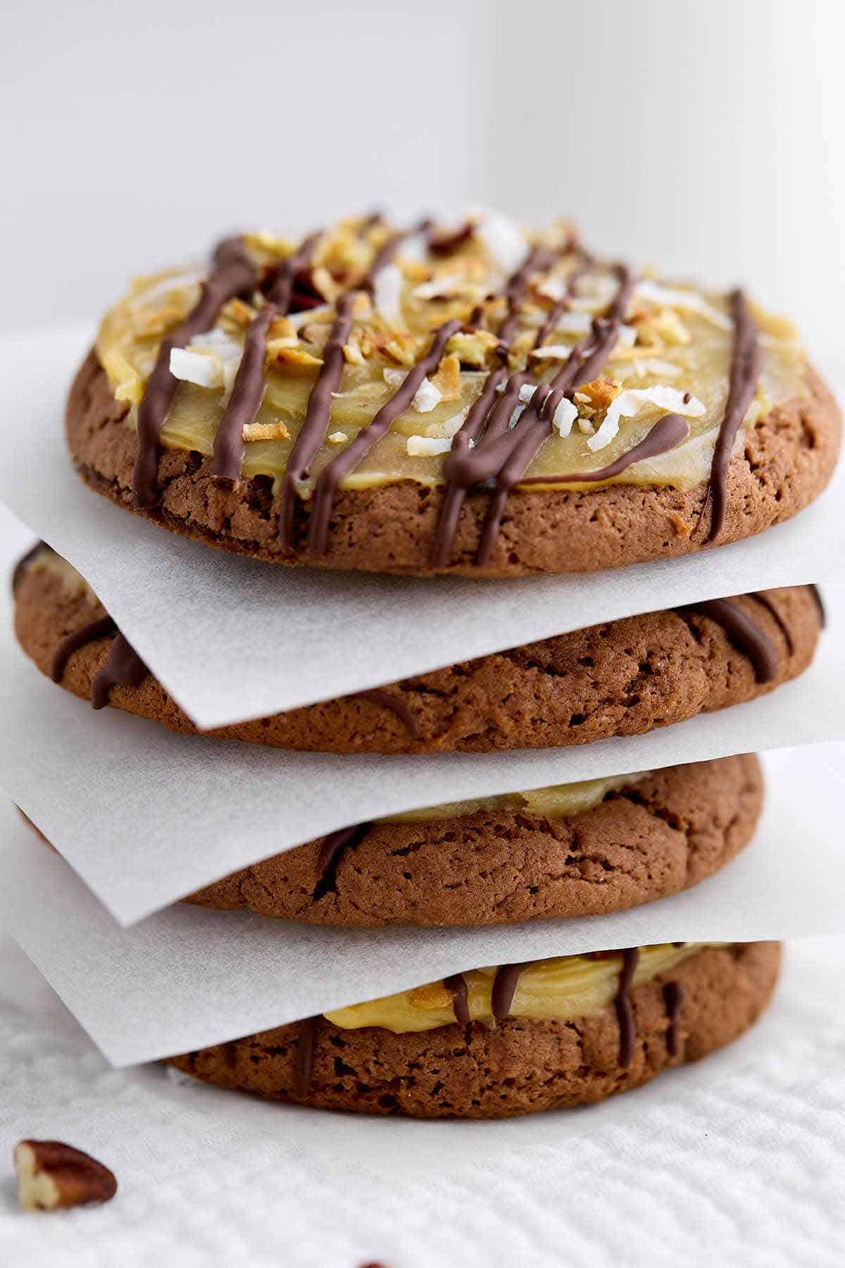 German chocolate cake mix cookies stack on top of each other with a parchment paper square in between each one.