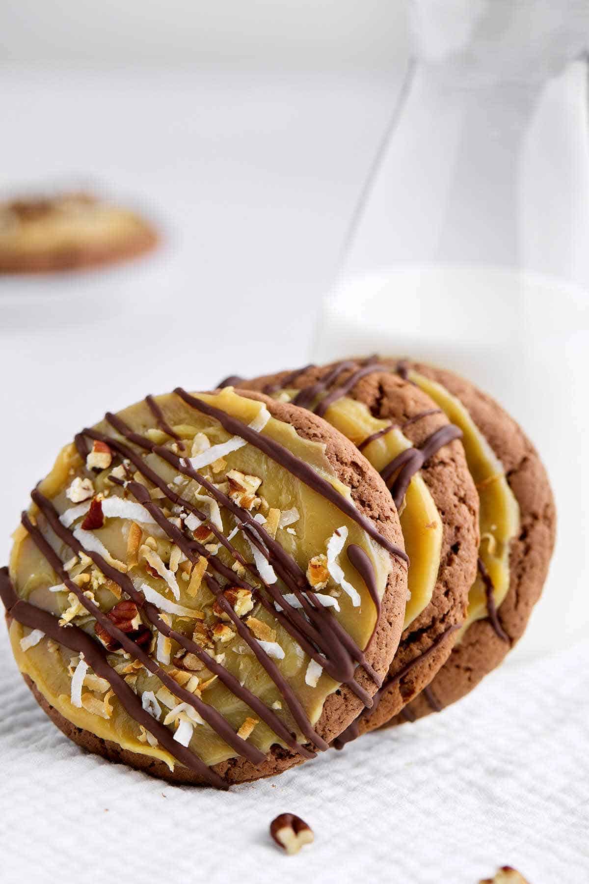 German chocolate cake mix cookies leaning against a glass of milk.