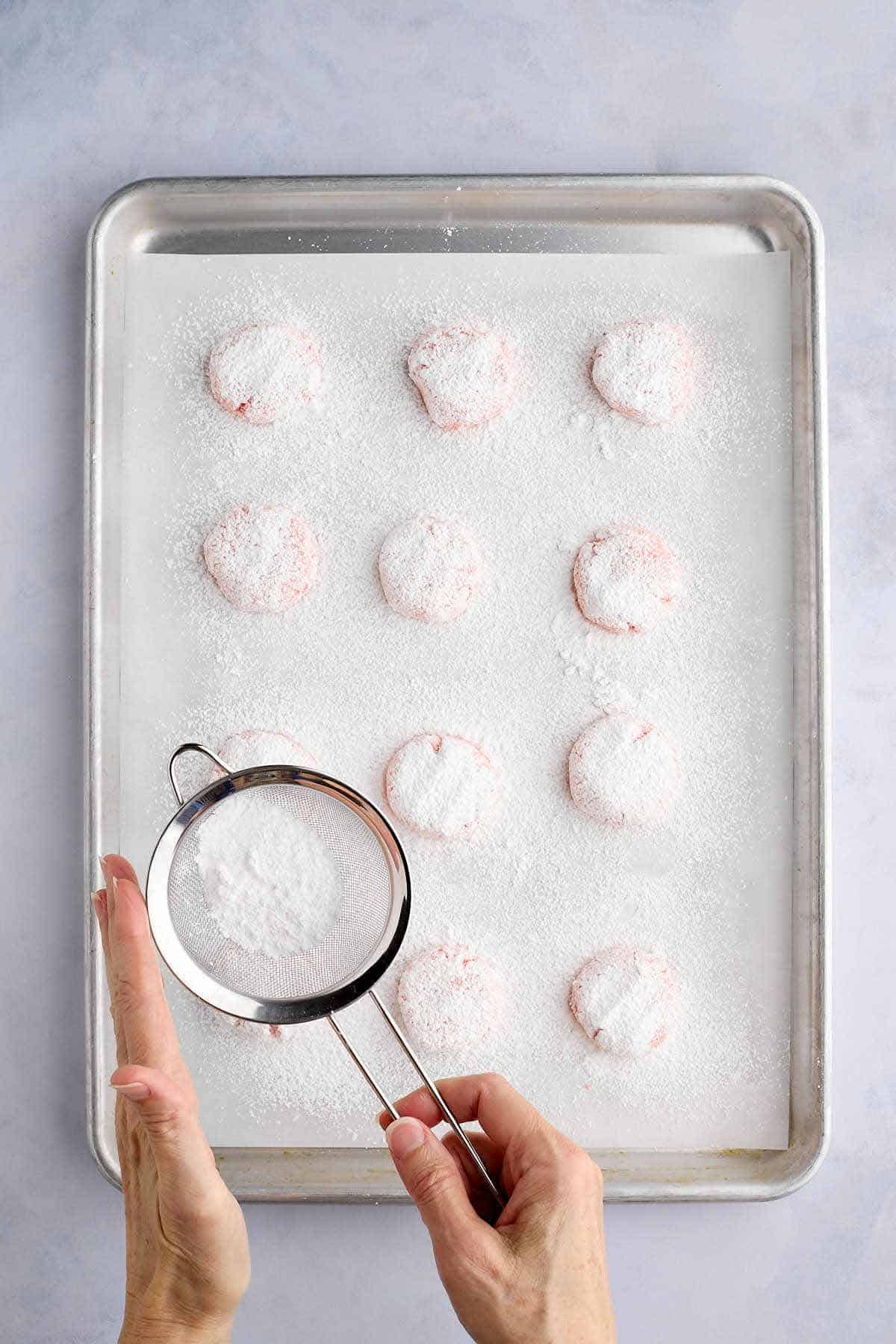 Sprinkling extra powdered sugar on cake mix strawberry crinkle cookie dough balls.