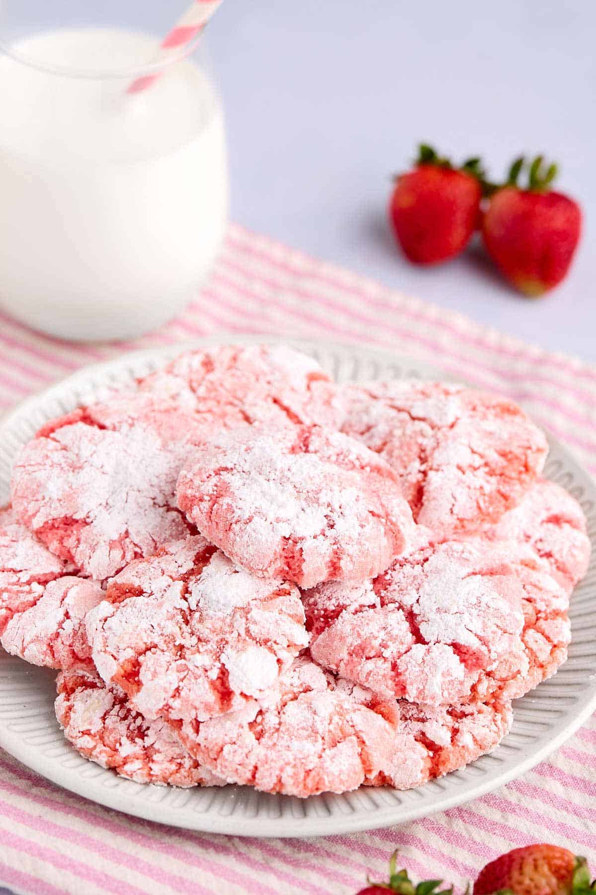 Plate of strawberry cake mix crinkle cookies with a cup of milk.