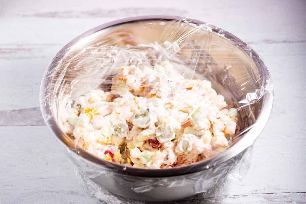 Ambrosia salad in a mixing bowl, covered and ready to be chilled.