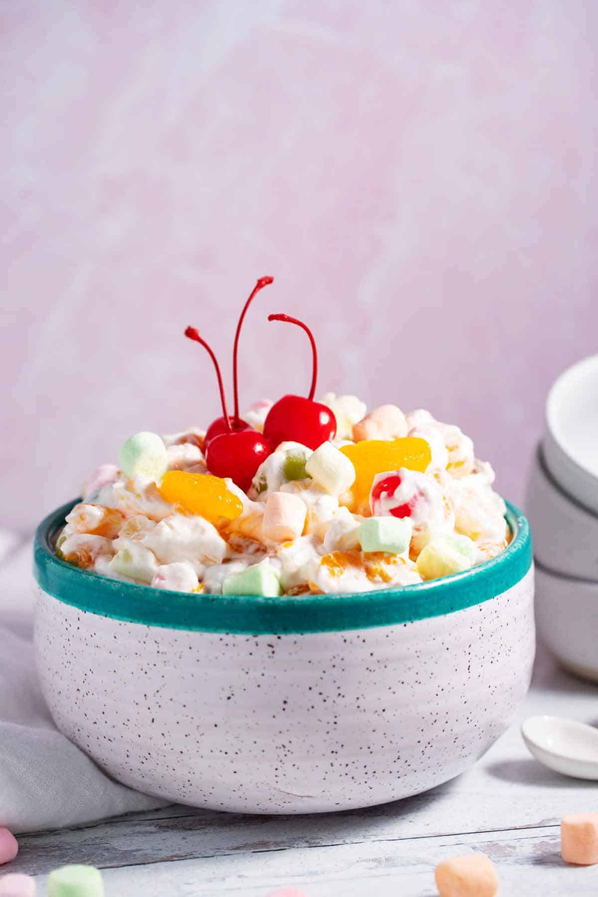Ambrosia salad with Cool Whip and cherries on top.