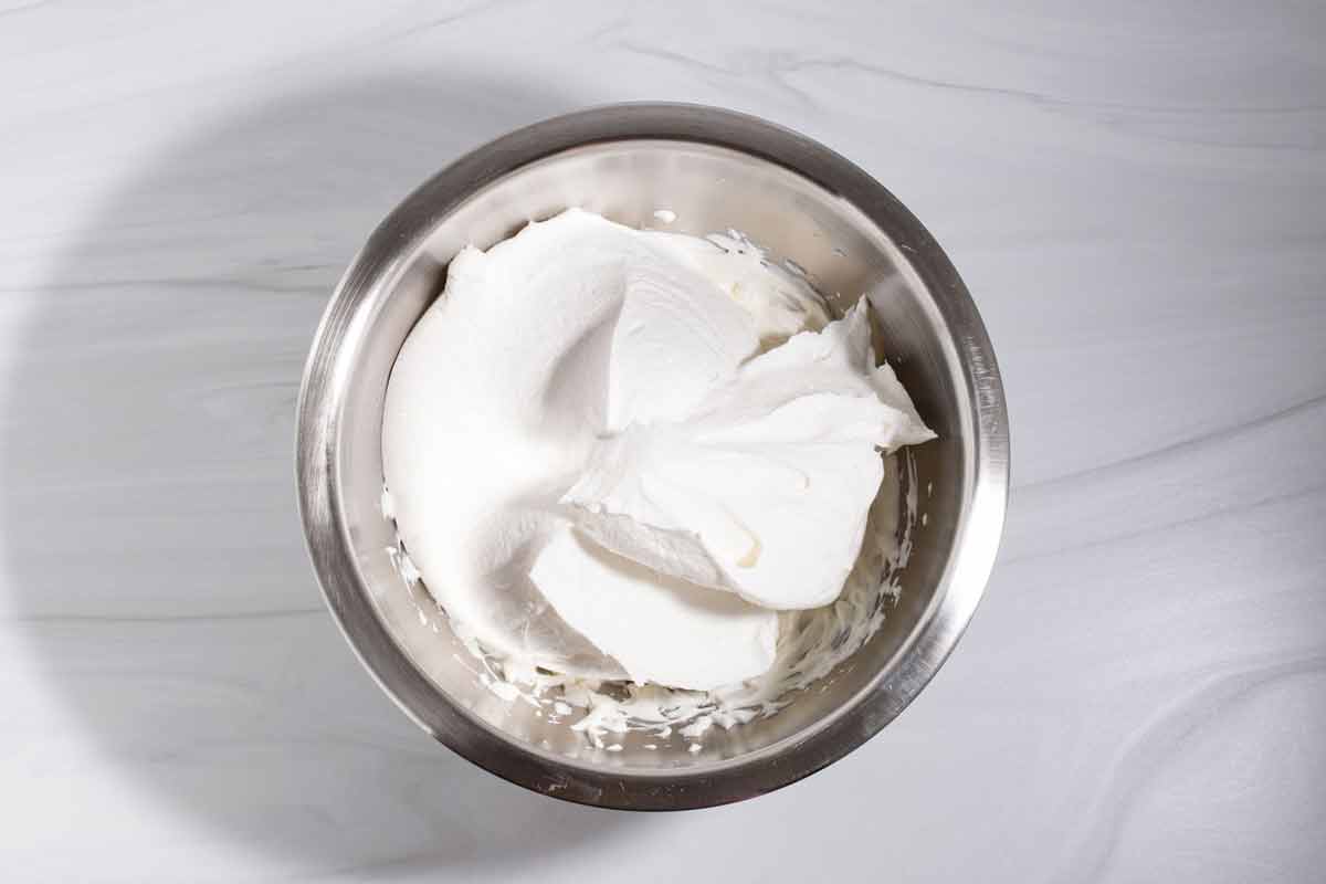 Cool Whip added to softened cream cheese in a bowl.