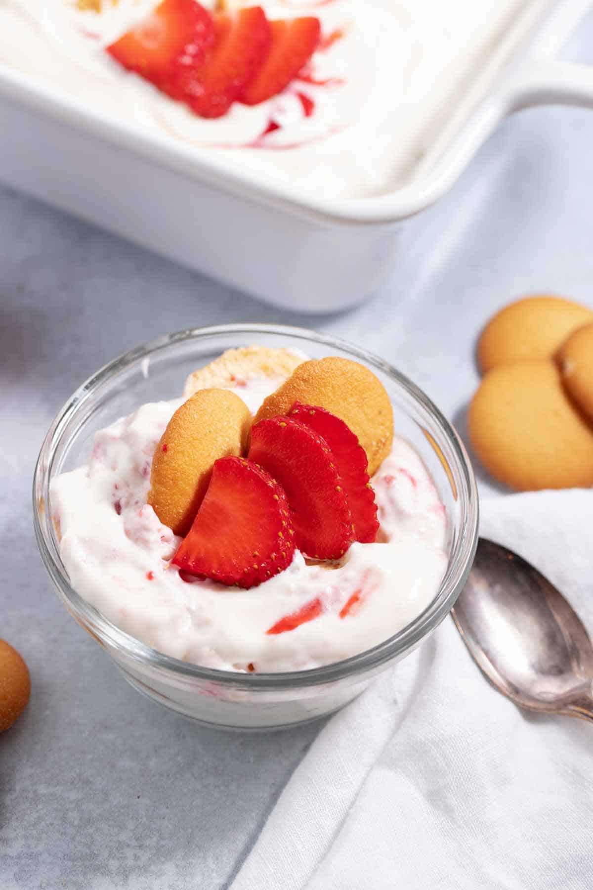 Bowl of strawberry banana pudding next to a serving dish.