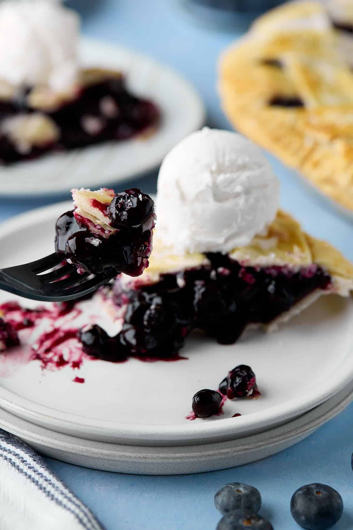 A fork holding a bite of blueberry pie.