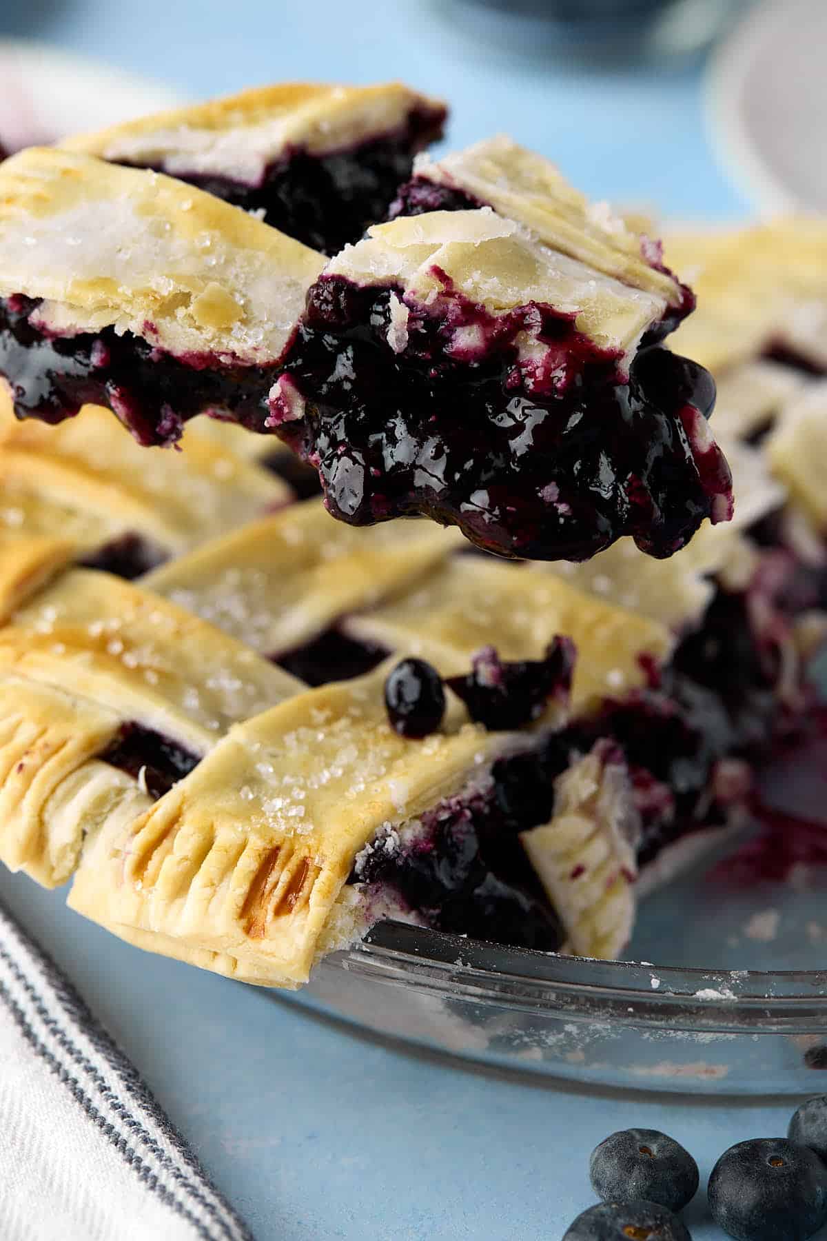 A blueberry pie slice being lifted from the pie tin.