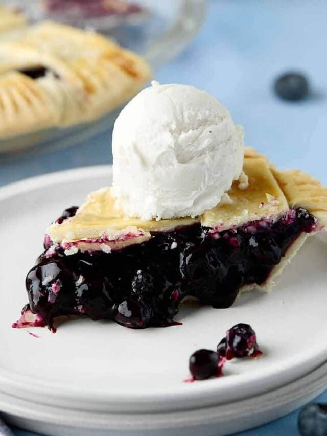 Slice of blueberry pie with canned filling with a scoop of ice cream on top.