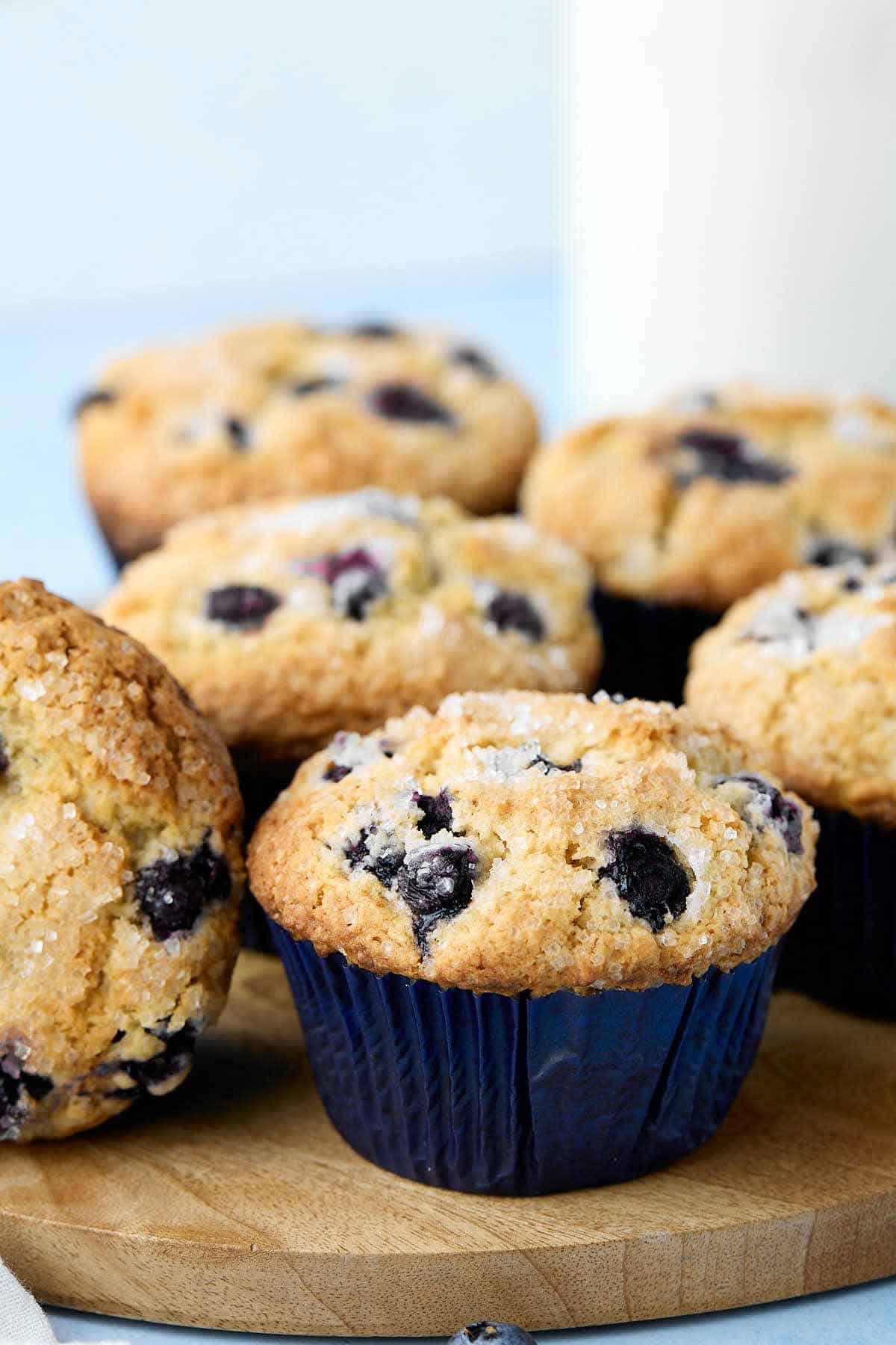 Jumbo blueberry buttermilk muffins on a wooden tray.