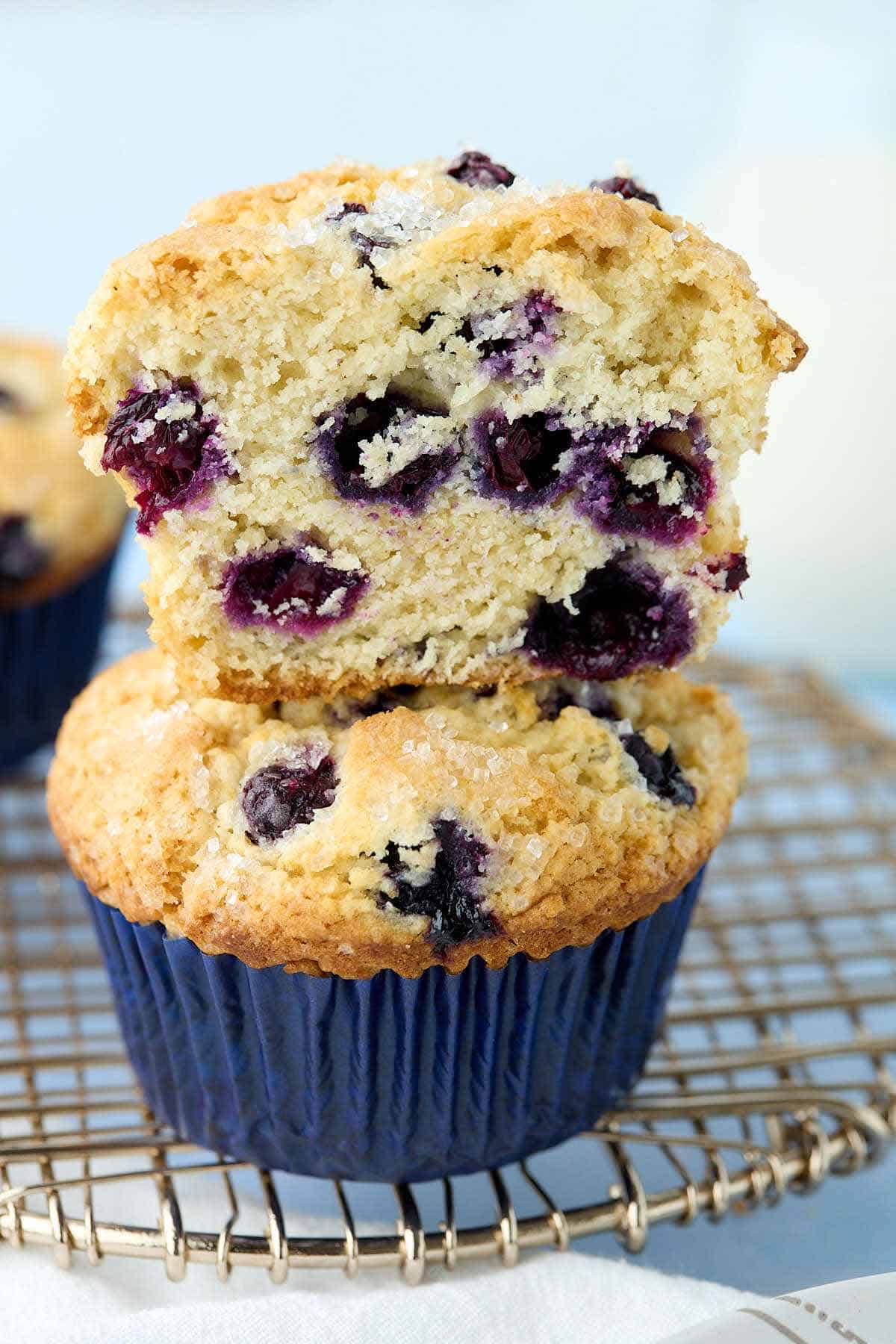 Two buttermilk blueberry muffins stacked with the top muffin cut in half to show the inside.