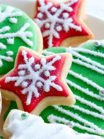 Stack of decorated Christmas sugar cookies on a plate.