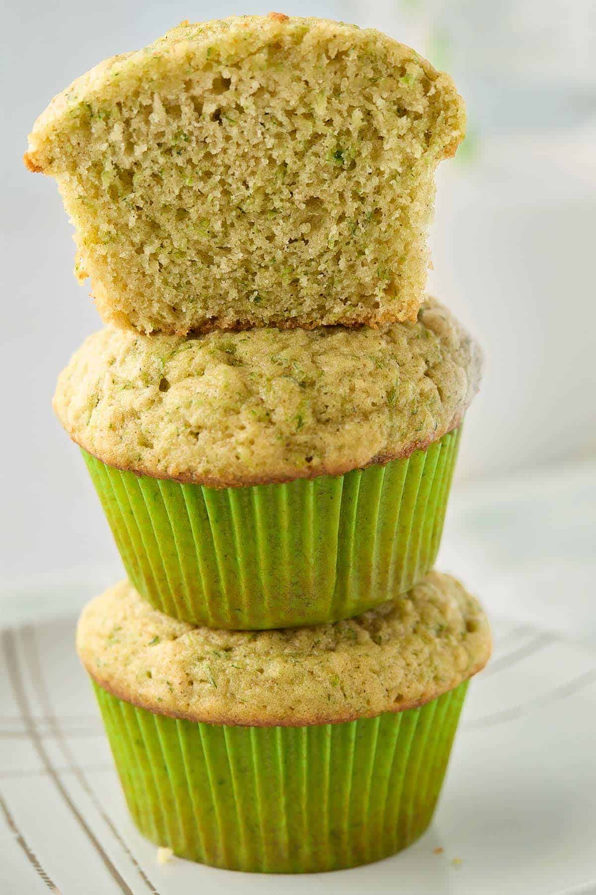 Stacked breakfast zucchini muffins with the top muffin cut in half to see the interior.