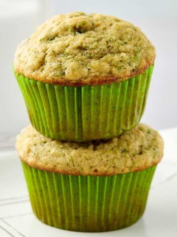 Two stacked zucchini muffins on a plate.