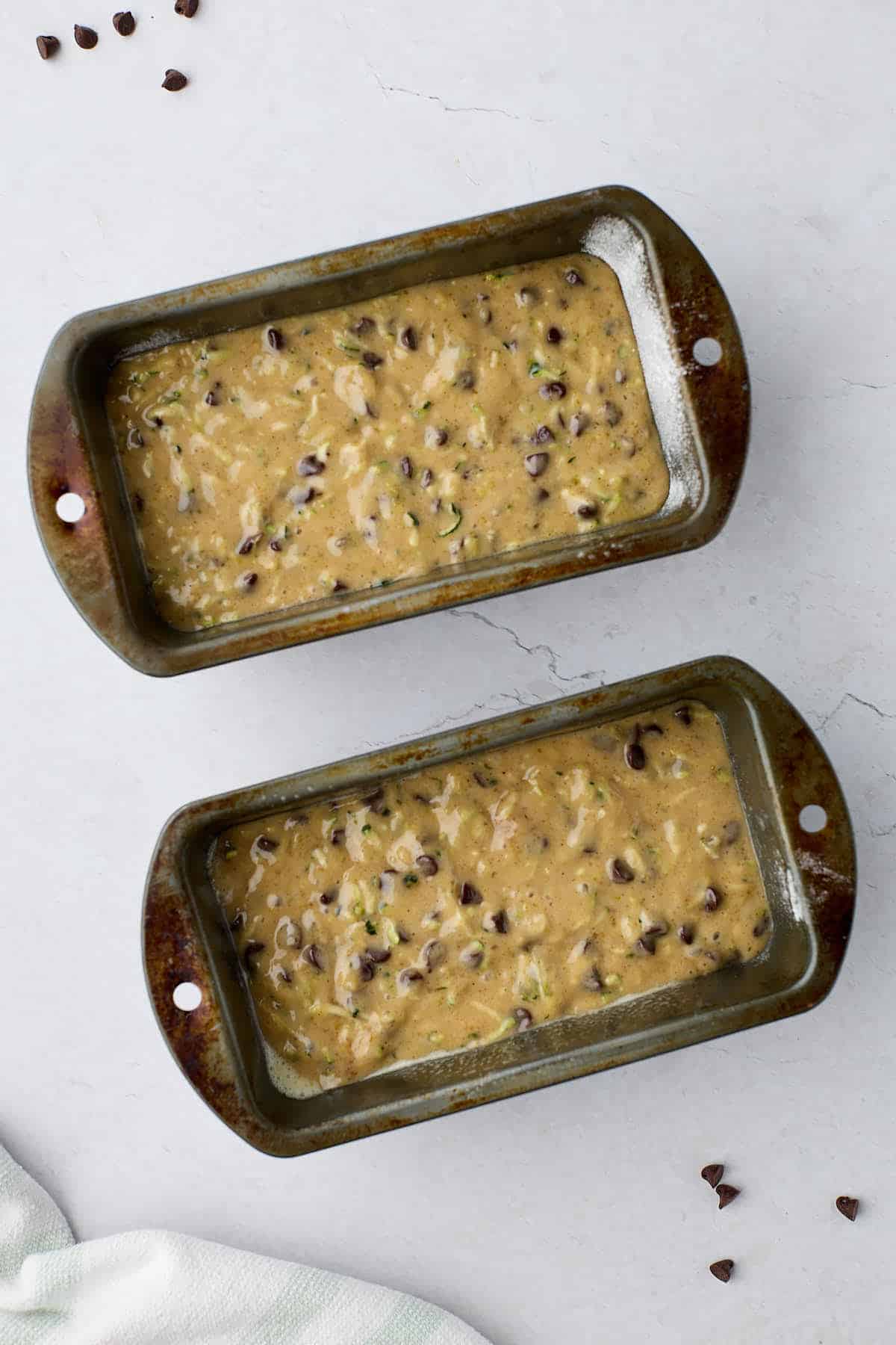 Mini loaf pans filled with zucchini loaf batter.