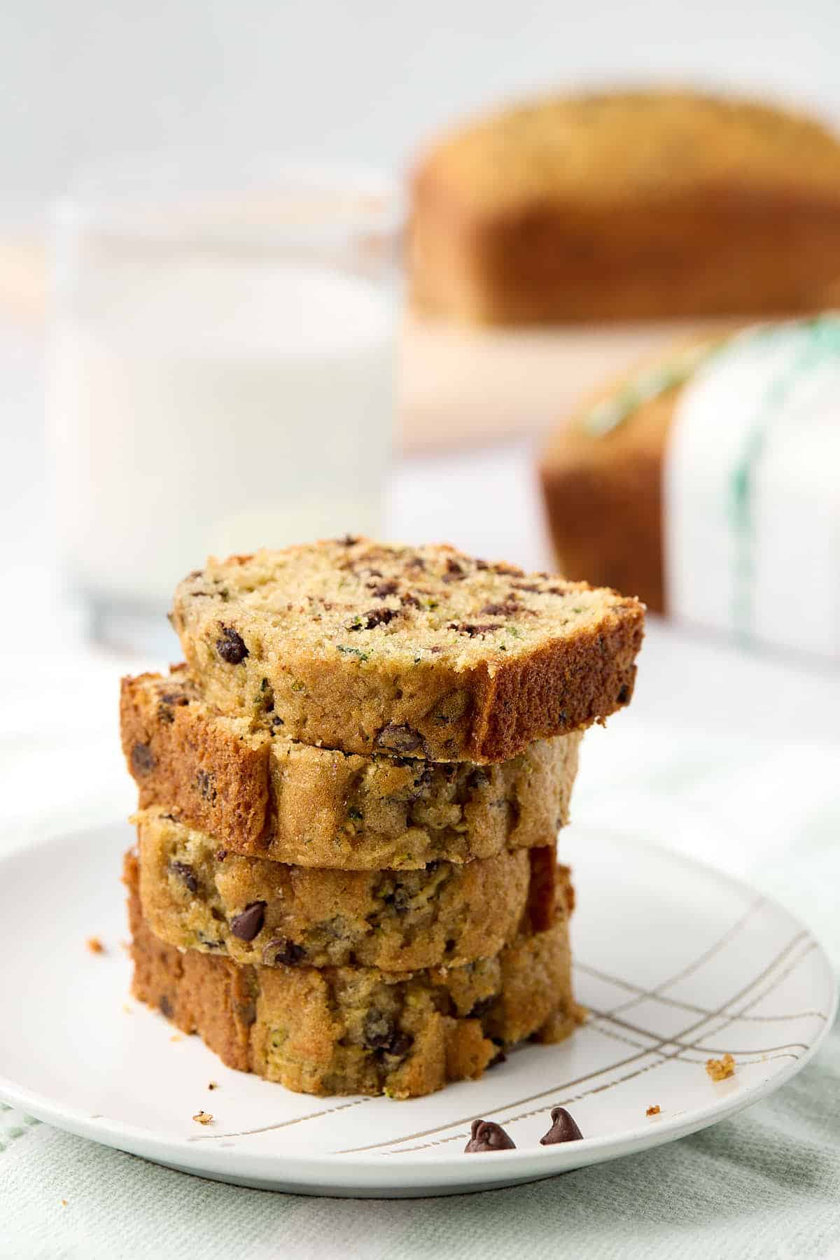 Stack of 4 slices of chocolate chip zucchini bread on a plate.